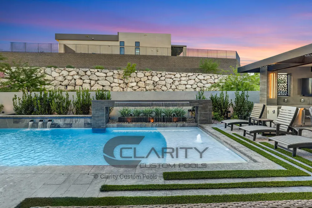 Pool at sunset with a framed sheer water feature, a bubbler on the shallow ledge and a concrete deck